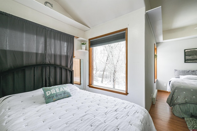 bedroom with hardwood / wood-style floors, baseboard heating, vaulted ceiling, and multiple windows