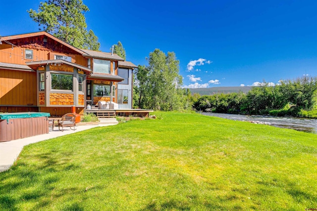 view of yard with a patio area, a deck with water view, and a hot tub