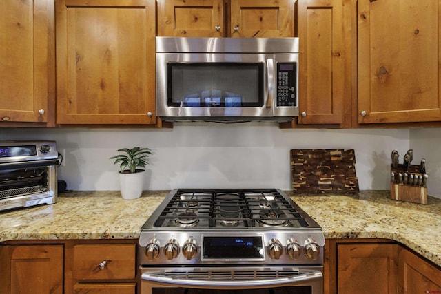 kitchen featuring appliances with stainless steel finishes and light stone counters