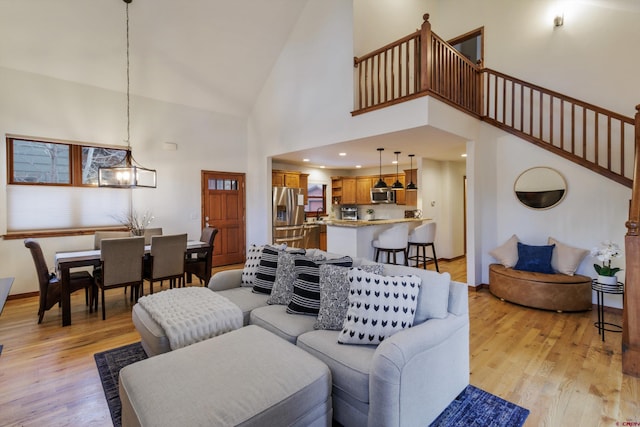 living room with light hardwood / wood-style floors, high vaulted ceiling, and a notable chandelier