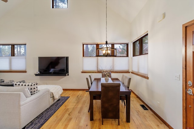 dining space featuring hardwood / wood-style floors, a high ceiling, and a notable chandelier