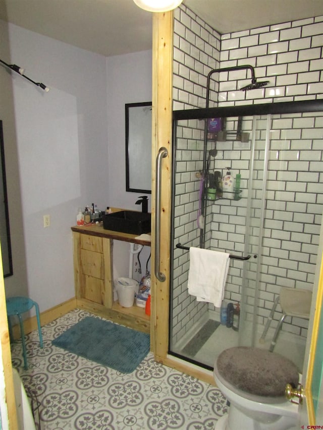 bathroom featuring toilet, a shower with shower door, and sink