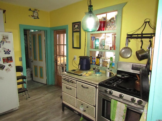 kitchen with hardwood / wood-style flooring, decorative light fixtures, stainless steel gas range oven, and white refrigerator