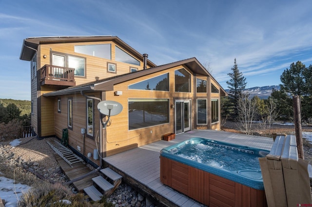 rear view of house with a wooden deck, a sunroom, a balcony, and a hot tub