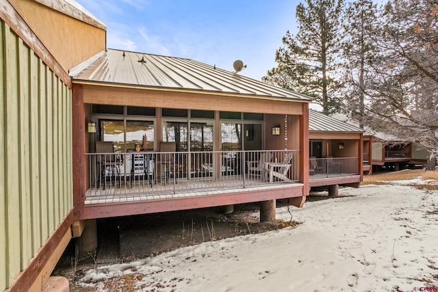 snow covered back of property featuring a wooden deck