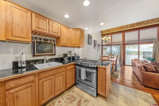 kitchen featuring kitchen peninsula, sink, an inviting chandelier, and stainless steel gas range