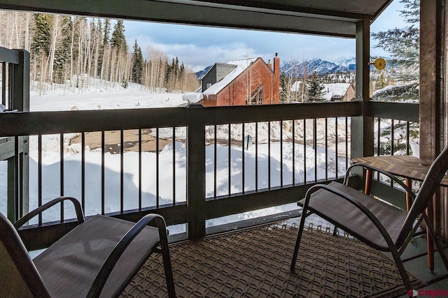 snow covered back of property featuring a mountain view