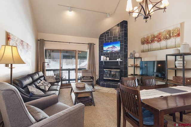 carpeted living room featuring a tile fireplace, high vaulted ceiling, track lighting, and an inviting chandelier