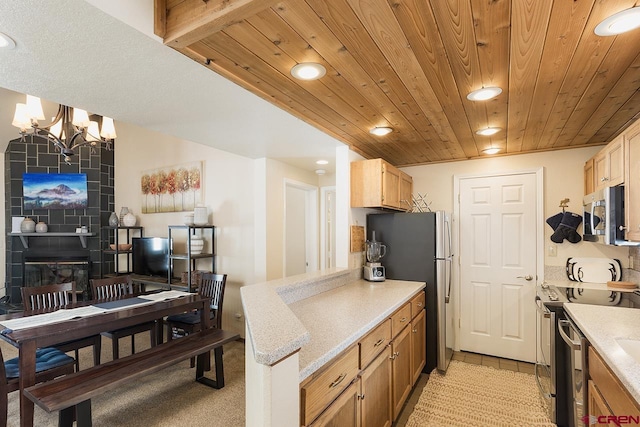 kitchen with a large fireplace, stainless steel appliances, wooden ceiling, a notable chandelier, and hanging light fixtures