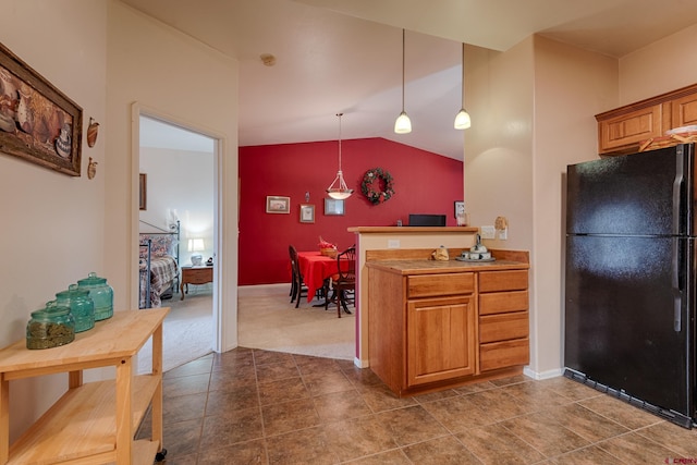 kitchen with vaulted ceiling, kitchen peninsula, black fridge, and decorative light fixtures