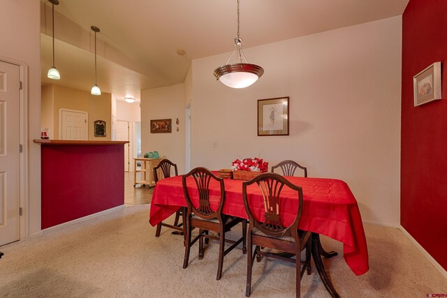 carpeted dining space with vaulted ceiling