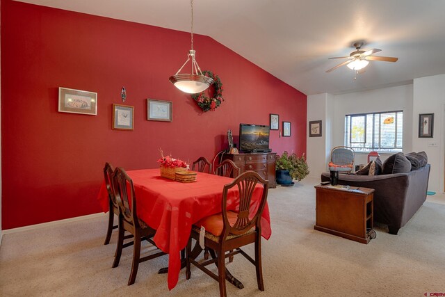 carpeted dining space with ceiling fan and lofted ceiling