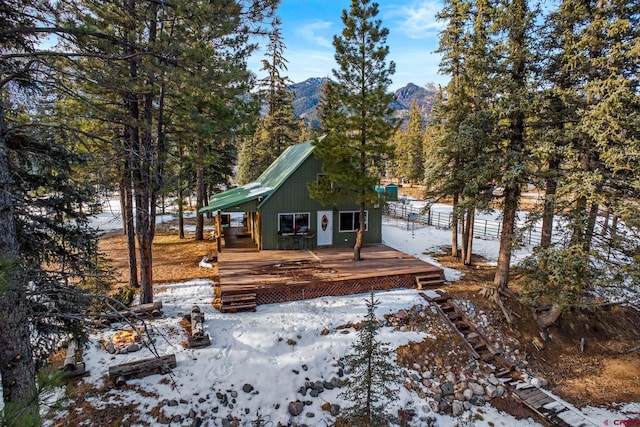 snow covered house featuring a deck with mountain view