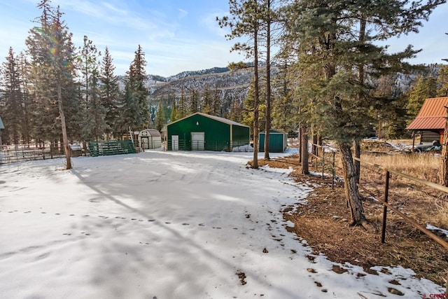 snowy yard featuring a mountain view and an outdoor structure