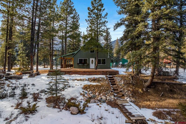 snow covered back of property featuring a deck