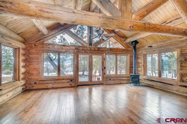 interior space with vaulted ceiling with beams, a wood stove, ceiling fan, and wood ceiling