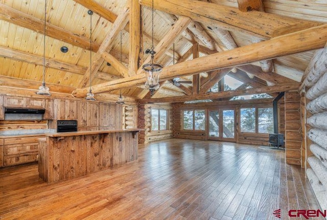 unfurnished living room with a wood stove, rustic walls, wood ceiling, and beam ceiling