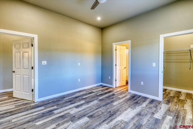 unfurnished bedroom with a walk in closet, dark hardwood / wood-style floors, a closet, and ceiling fan