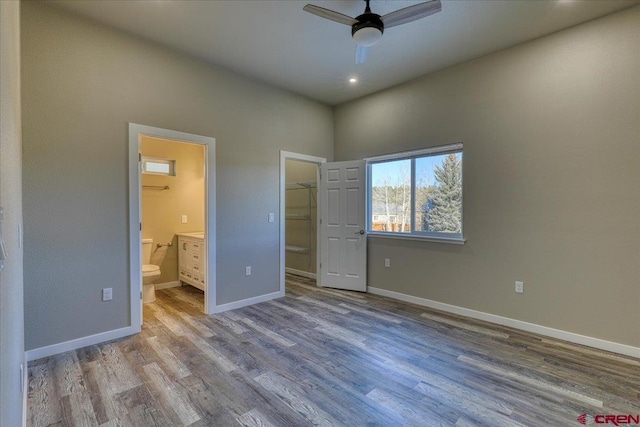 unfurnished bedroom with ensuite bath, ceiling fan, a spacious closet, light hardwood / wood-style floors, and a closet