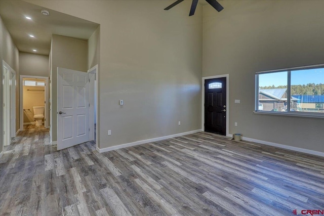 empty room featuring a high ceiling, ceiling fan, and wood-type flooring