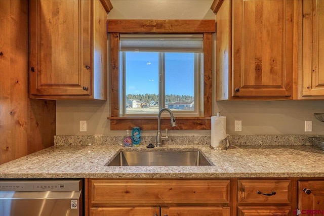 kitchen with dishwasher, light stone countertops, and sink