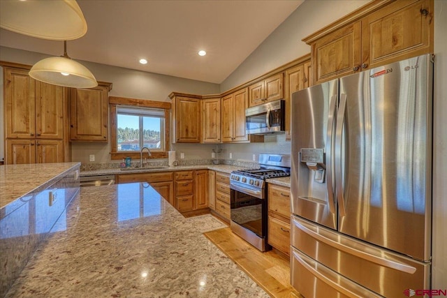 kitchen with light stone counters, stainless steel appliances, sink, decorative light fixtures, and lofted ceiling