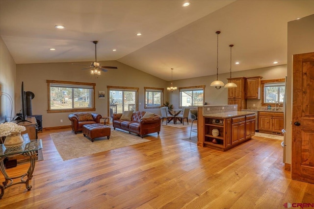 living room with ceiling fan with notable chandelier, light hardwood / wood-style flooring, lofted ceiling, and sink