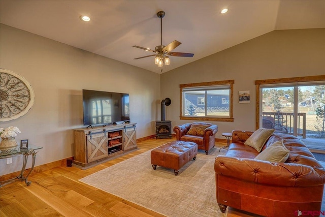 living room featuring hardwood / wood-style flooring, lofted ceiling, ceiling fan, and a wood stove