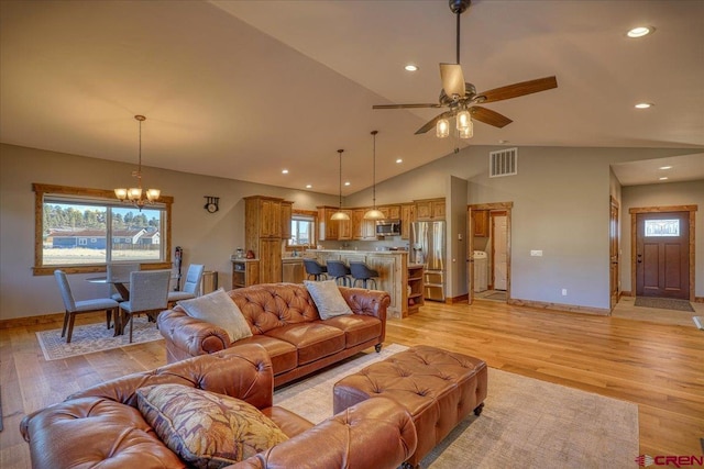 living room with ceiling fan with notable chandelier, light hardwood / wood-style floors, and lofted ceiling