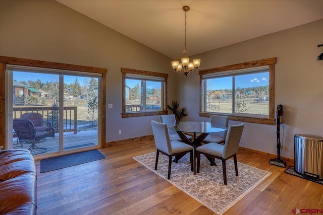 dining space with a chandelier, wood-type flooring, and high vaulted ceiling