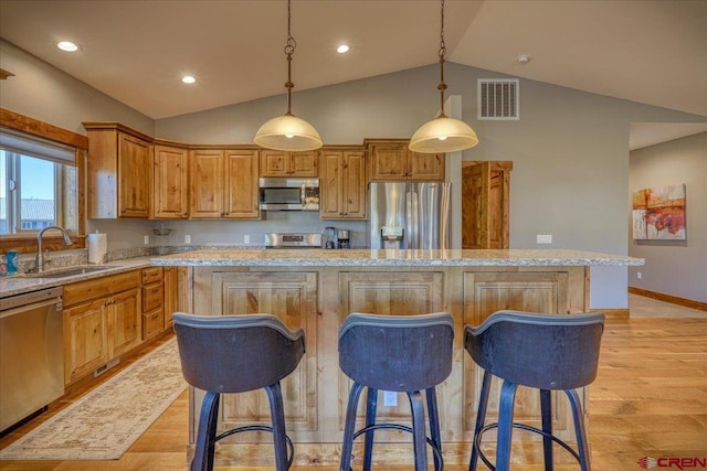 kitchen featuring sink, hanging light fixtures, light hardwood / wood-style flooring, a kitchen island, and stainless steel appliances