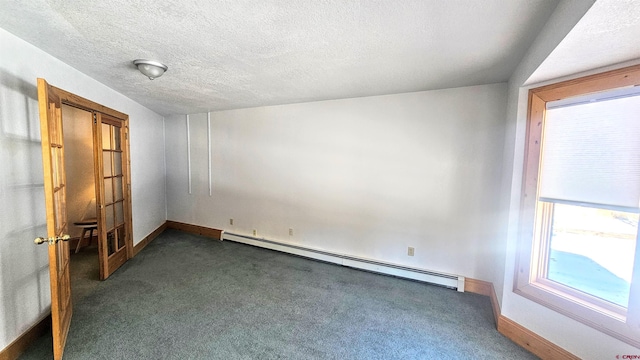 carpeted empty room with a textured ceiling and a baseboard heating unit