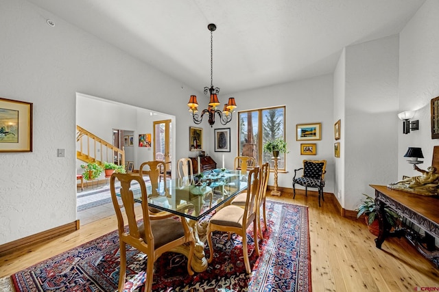 dining space featuring light hardwood / wood-style floors, vaulted ceiling, and a notable chandelier