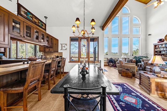 dining area with ceiling fan with notable chandelier, sink, light tile patterned floors, a towering ceiling, and beamed ceiling