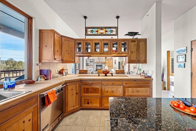 kitchen featuring pendant lighting, lofted ceiling, light tile patterned floors, kitchen peninsula, and stainless steel appliances