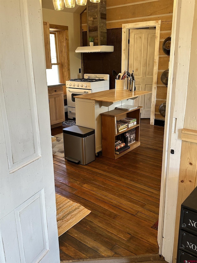 kitchen featuring white gas stove, dark wood-type flooring, extractor fan, and a breakfast bar area