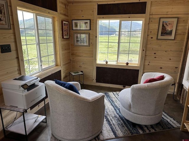 sitting room featuring a wealth of natural light, radiator, and wooden walls