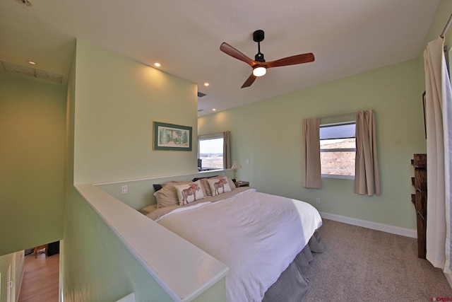 carpeted bedroom featuring multiple windows and ceiling fan