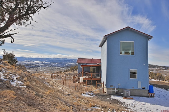 view of snowy exterior featuring a mountain view and central AC unit