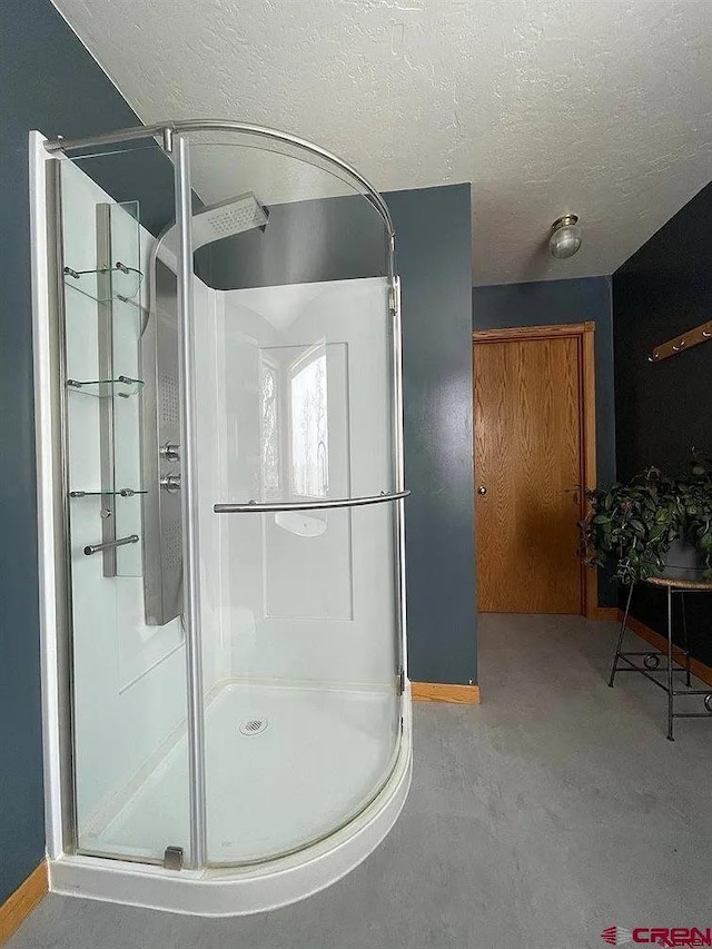 bathroom with a textured ceiling, concrete floors, and walk in shower