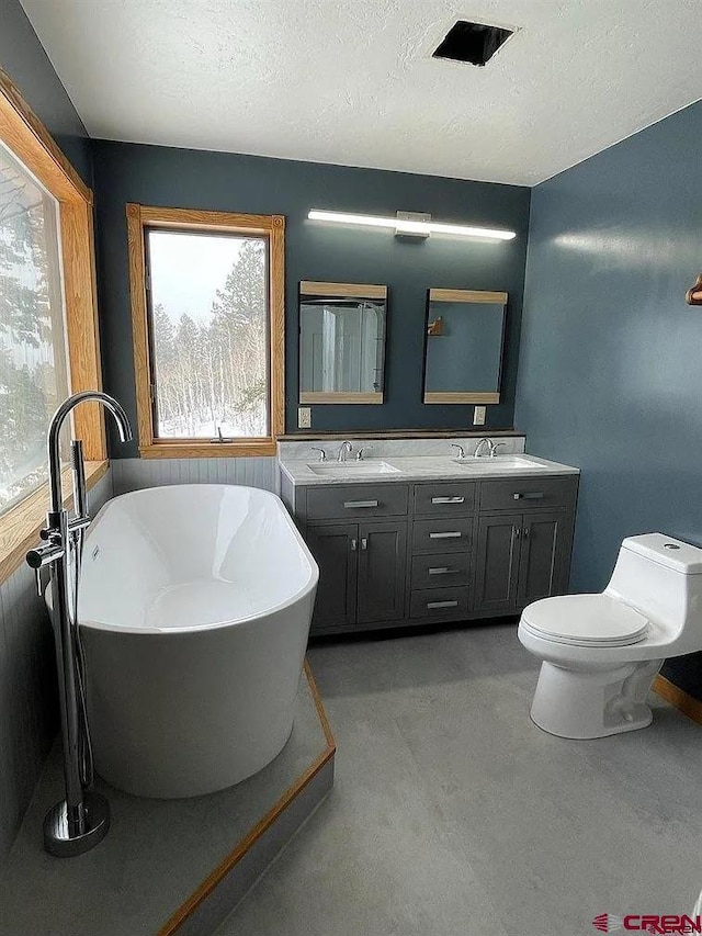 bathroom with toilet, vanity, a tub, and a textured ceiling