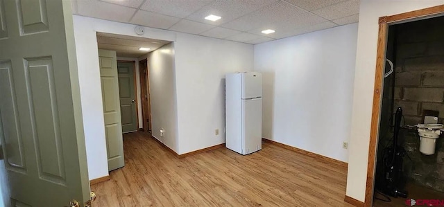 interior space featuring a drop ceiling, white refrigerator, and light hardwood / wood-style flooring