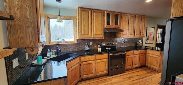 kitchen featuring decorative light fixtures, stainless steel appliances, sink, backsplash, and light hardwood / wood-style flooring