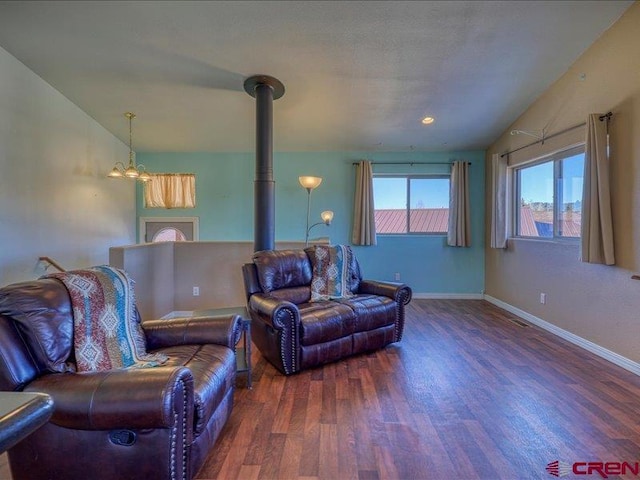 living room with dark hardwood / wood-style floors, a wood stove, a chandelier, and lofted ceiling