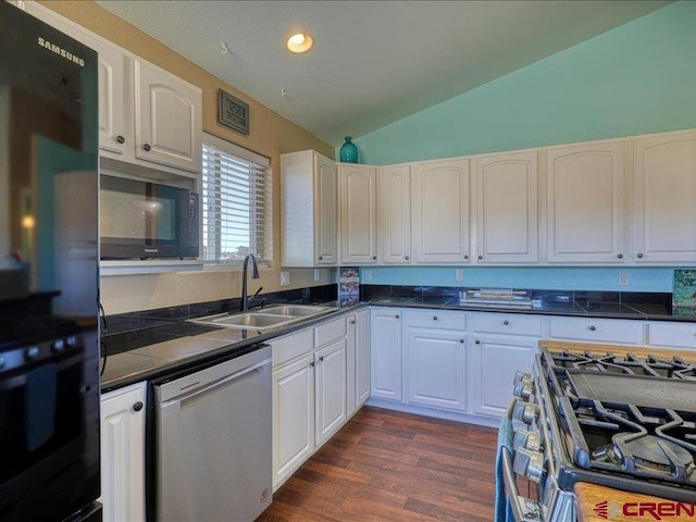 kitchen featuring lofted ceiling, dark wood-type flooring, white cabinets, sink, and stainless steel appliances