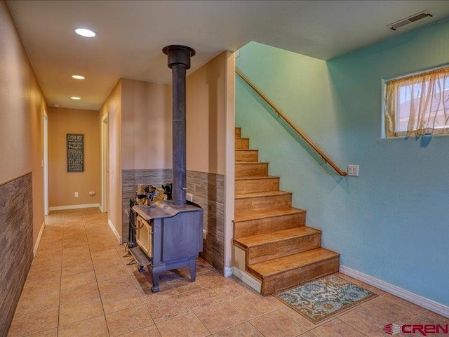 stairway featuring tile patterned flooring and a wood stove