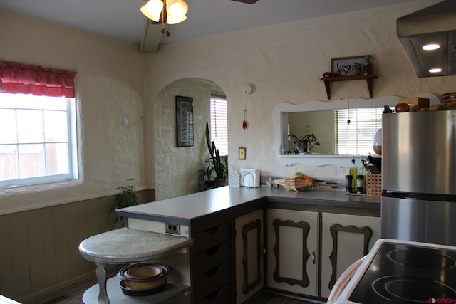 kitchen featuring kitchen peninsula, stove, stainless steel refrigerator, and plenty of natural light