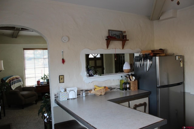 kitchen featuring beamed ceiling and stainless steel fridge