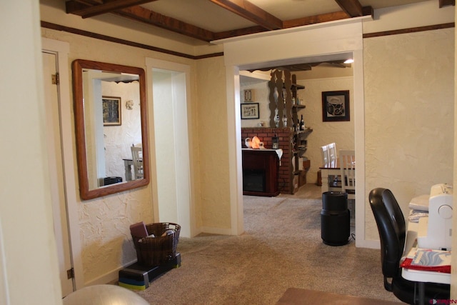 office space with carpet flooring, beam ceiling, and a brick fireplace