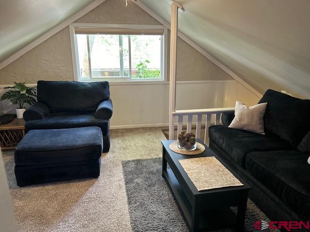 carpeted living room with lofted ceiling